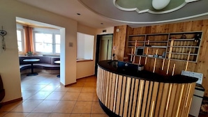 Zona de recepción con un mostrador de madera, una pared curva y vista a un comedor.