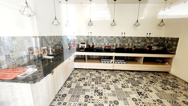 Una cocina con baldosas estampadas, lámparas colgantes y una encimera con varios electrodomésticos.