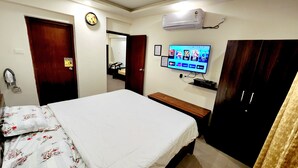 Una habitación de hotel con cama, televisor, armario, mesita de noche y aire acondicionado instalado en la pared.