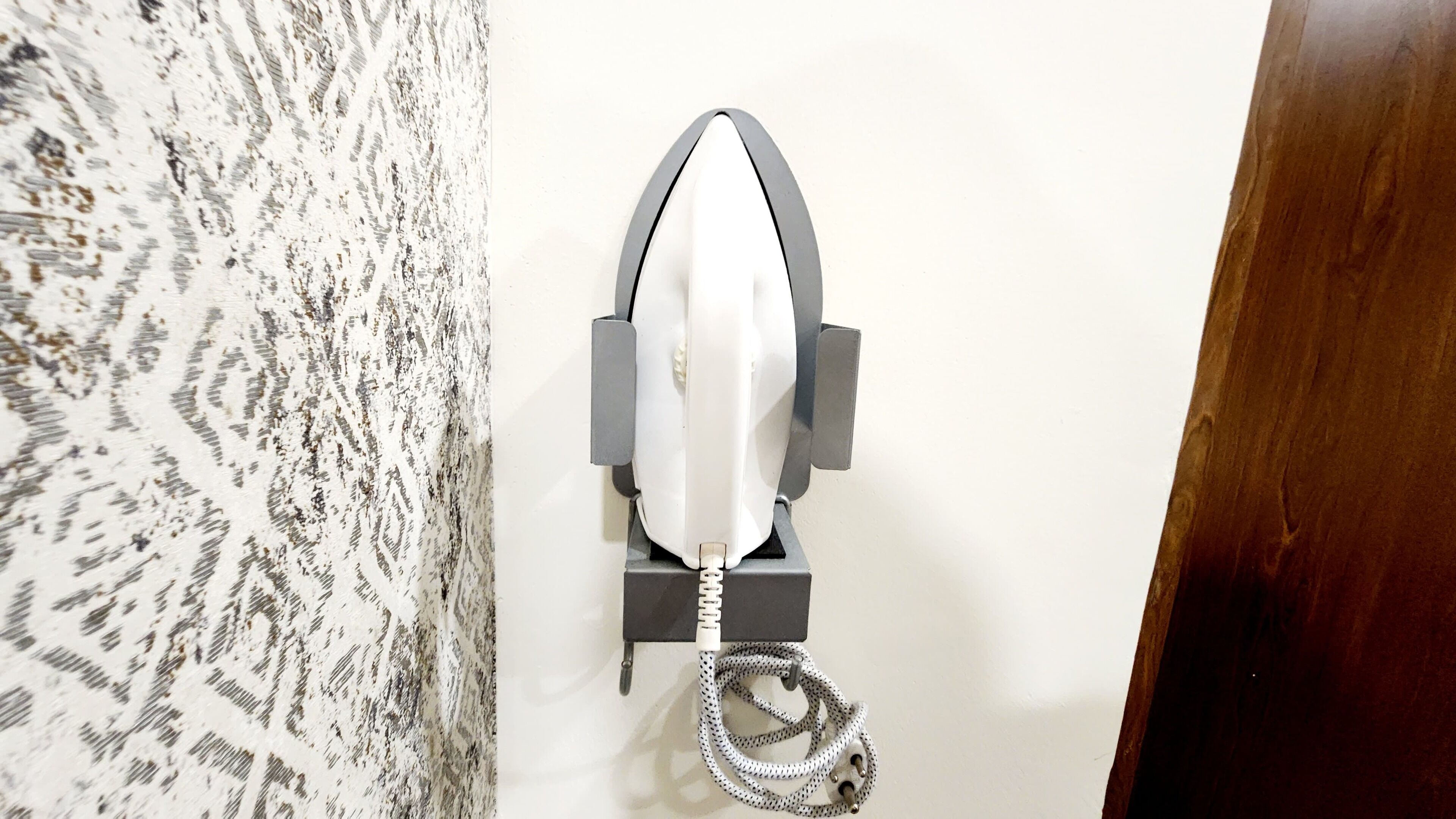 A wall-mounted object with a coiled cable, a metal frame, and a white plastic component.