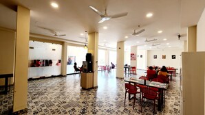 Un restaurante espacioso con techos altos, varios ventiladores de techo y suelo estampado.