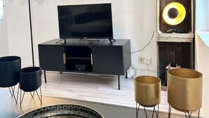 Een moderne woonkamer met een flatscreen televisie, twee ingelijste kunstwerken, een decoratieve schedel en een bijzondere ronde lamp.