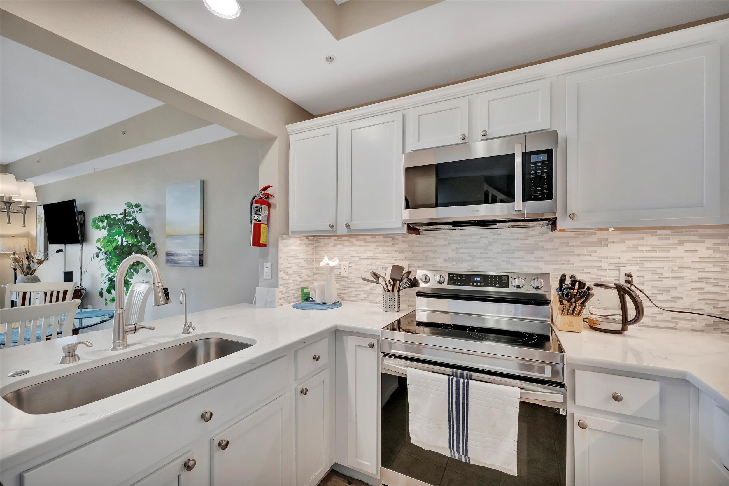 A modern kitchen with white cabinetry, stainless steel appliances, and a tiled backsplash.