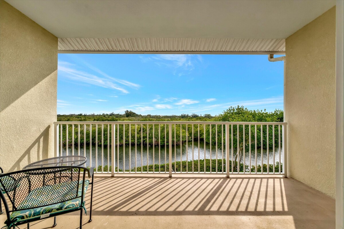 A balcony with a view of a body of water, a metal table, and a chair.