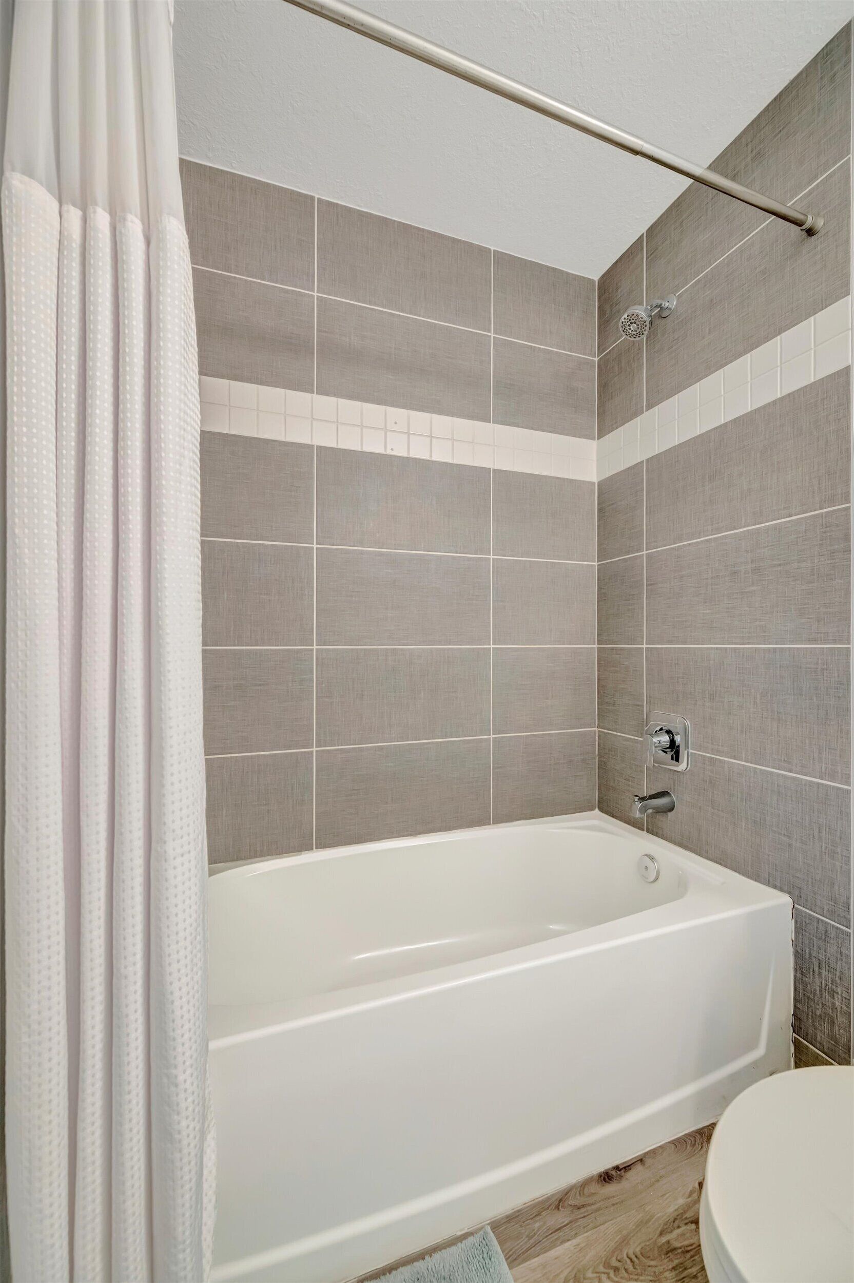 A bathroom with a bathtub, a showerhead, and a toilet.