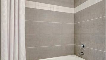 A bathroom with a bathtub, a showerhead, and a toilet.
