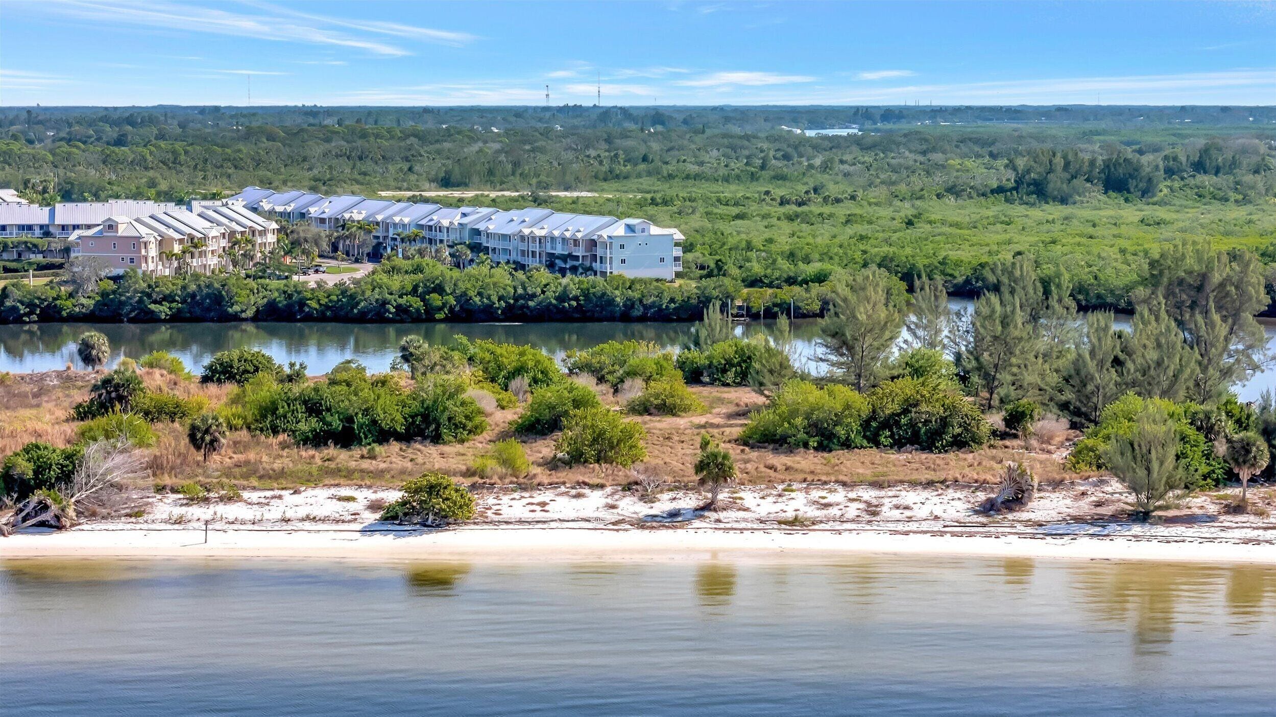 Ein Küstenhotel mit mehrstöckigen Gebäuden, einem Sandstrand und einem Fluss.