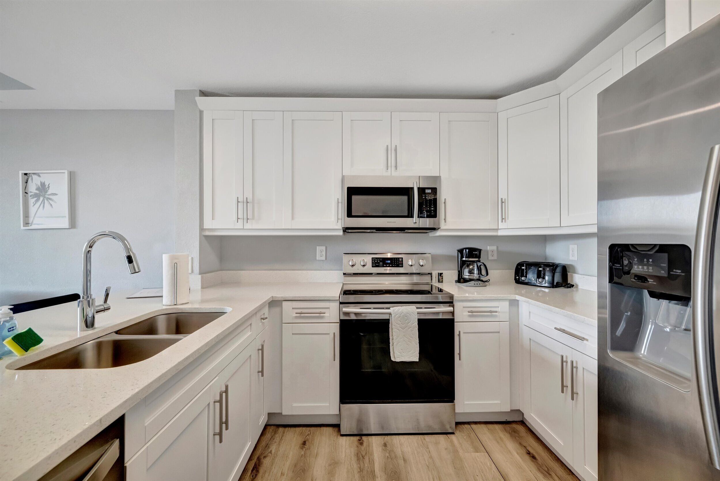 A modern kitchen with white cabinets, stainless steel appliances, a double sink, and a coffee maker.