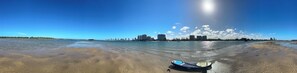 A beach with a boat, clear water, and a distant city skyline. - Waterfront Gold Coast Luxury apartment on the Lagoon (Labrador)