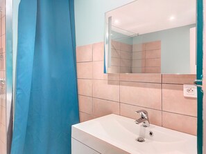 Un bagno con lavandino bianco, uno specchio e una tenda da doccia blu.