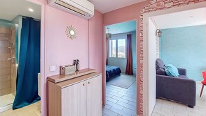 Ein Zimmer mit Bett, Badezimmer mit Dusche, Klimaanlage und Blick nach außen.