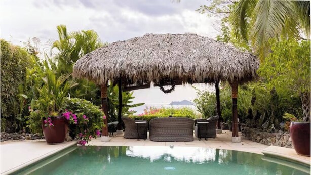 A pool with a thatched gazebo, wicker furniture, and tropical plants. - CasaMyra American Gourmet Breakfast Included (Playa Panama, Papagyo Bay)