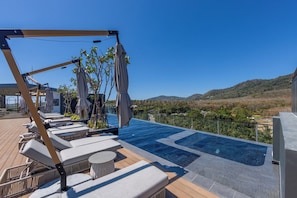 A rooftop pool area with lounge chairs and umbrellas, overlooking a mountainous landscape. - Harmony by TropicLook | Pool & Gym Access | Rawai (Rawai)