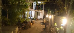 A courtyard with a building, trees, and a well-lit area. - Jungle Lodge & Camping site (Arusha)