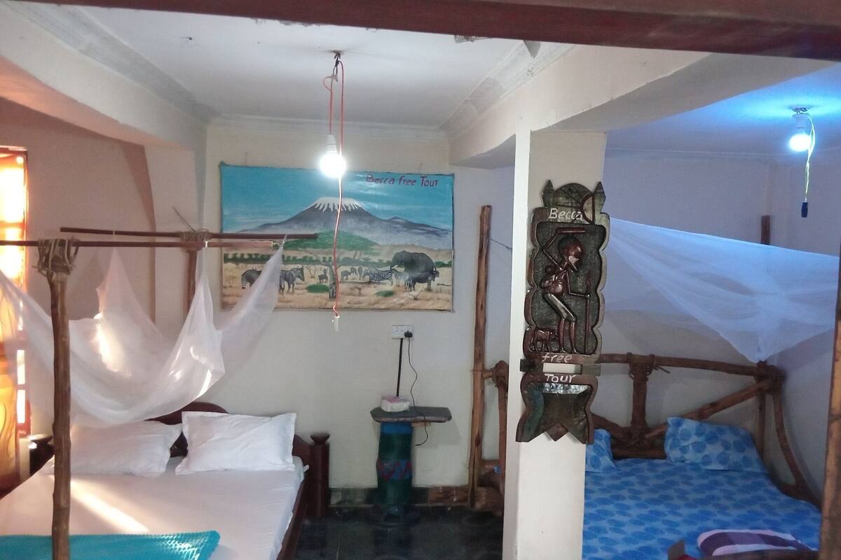 Habitació amb un llit, una cadira penjant, un quadre i un cartell que anuncia una visita gratuïta.