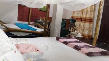 Une pièce comprenant un lit, une chaise, une table avec une lampe et un rideau.