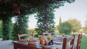 An outdoor dining table set with breakfast items, surrounded by greenery. - L'ANTIGO GRANARO (Ancona)