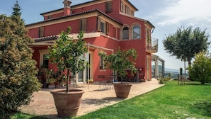 A two-story house with a red facade, a balcony, and a paved driveway. - L'ANTIGO GRANARO (Ancona)