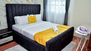 Een hotelkamer met een bed, een nachtkastje, een raam met gordijnen en een strijkijzer op een tafel.