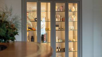 A modern interior with a wooden reception desk, a glass display cabinet with various items, and a ceiling vent.
