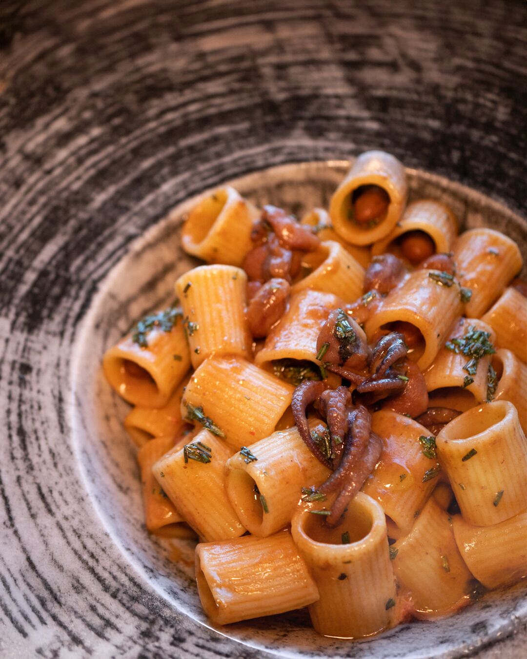A bowl of pasta with a creamy sauce and herbs.