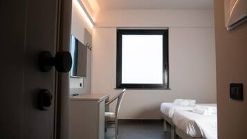 Habitación de hotel con cama, escritorio, silla, televisor y ventana.