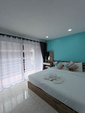 A hotel room with a bed, a wooden nightstand, a mirror, and a window with sheer curtains. - Dream Nest Patong Hotel Patong (Patong)