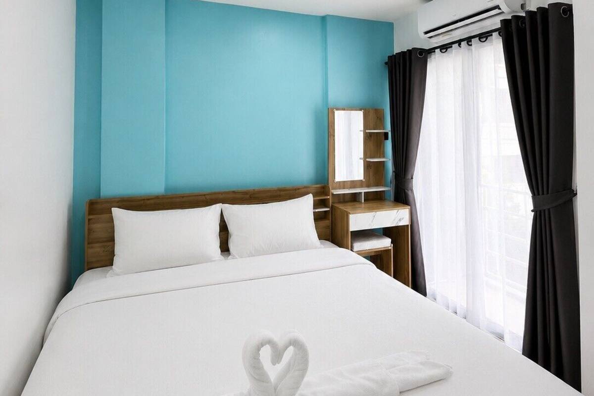 Ein Hotelzimmer mit Bett, Nachttisch, Spiegel und Klimaanlage.
