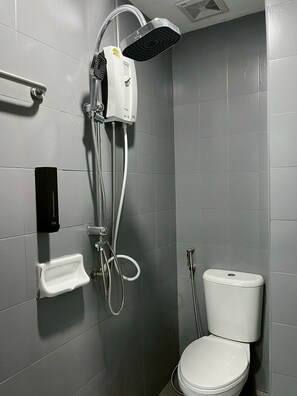 A bathroom with a shower, toilet, and a soap dispenser on the wall. - Dream Nest Patong Hotel Patong (Patong)