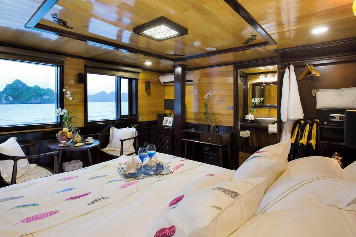 Una habitación con cama, una mesa con bandeja, una silla, una ventana con vista al mar y un espejo.