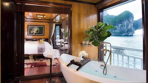 A room with a bathtub, wooden flooring, a view of the water, and a dining area with a table and chairs. - LAN HA BAY  STAR CRUISE  (Tuan Chau)