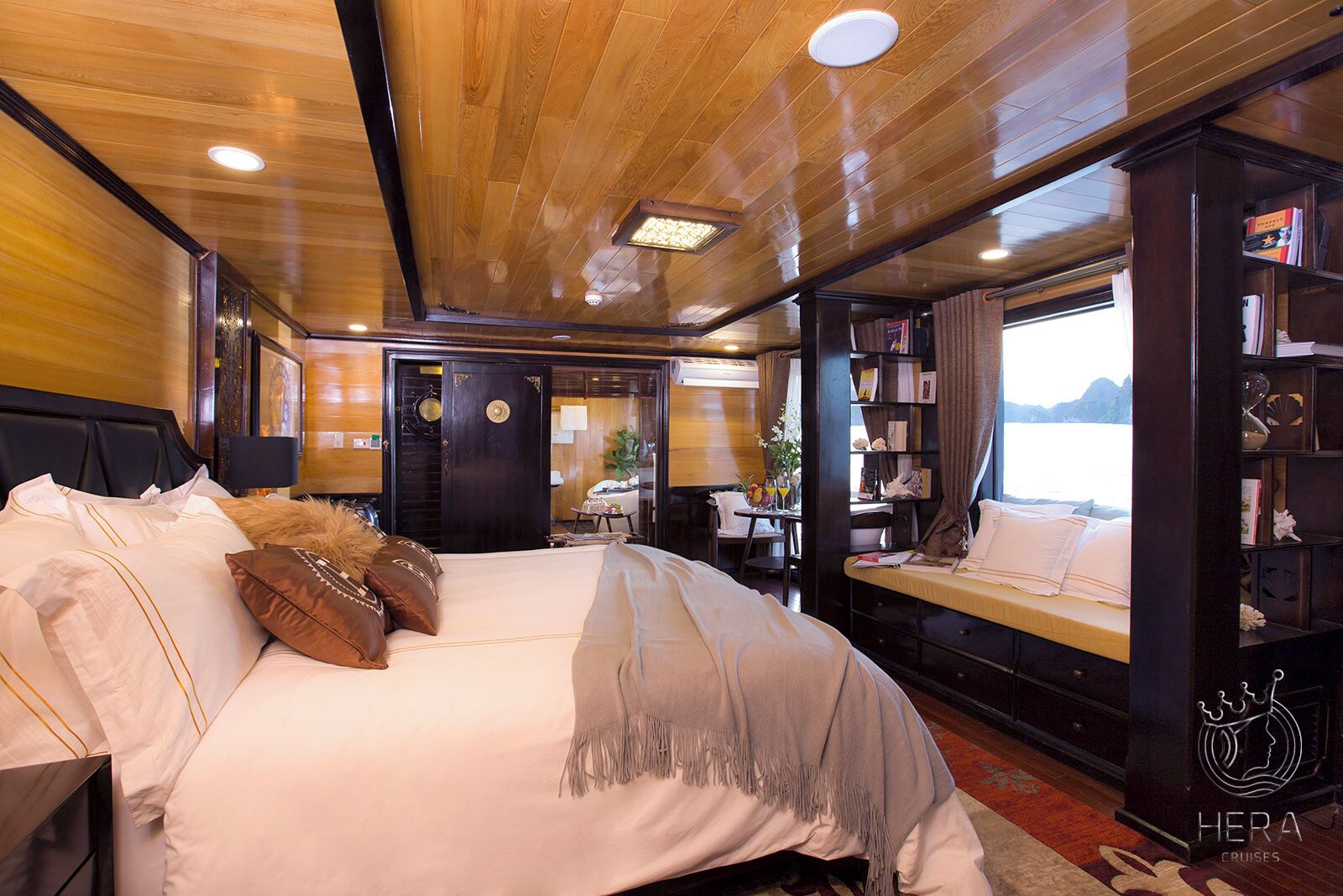 A cozy cabin with a large bed, a reading nook, and a view of the water.