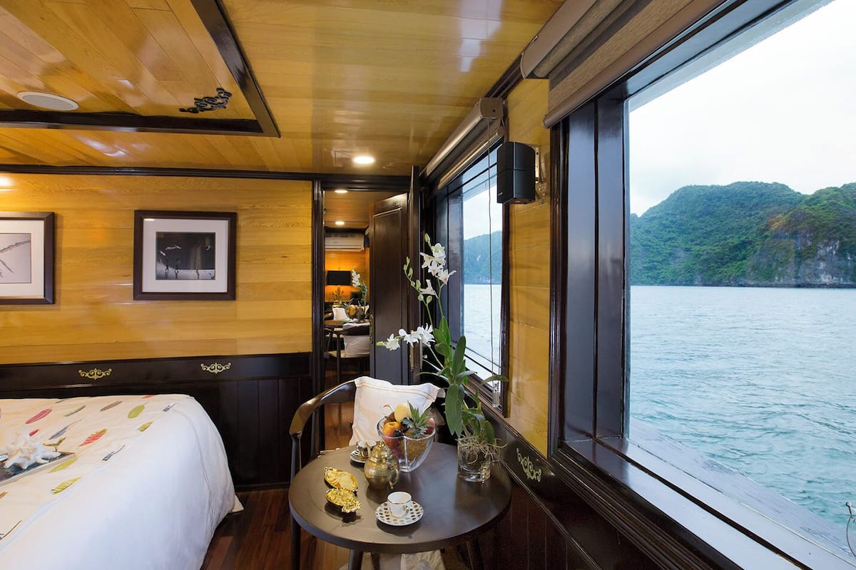 Una habitación con una cama, una mesa con un florero y vistas a un lago.