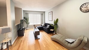 A living room with a sofa, a coffee table, a lamp, a clock, and a plant.