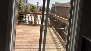 A view through a window with a wooden deck and a metal railing.