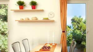 A dining area with a table, chairs, a clock, and potted plants on shelves. - Apartment in Cogoleto with pool (Cogoleto)
