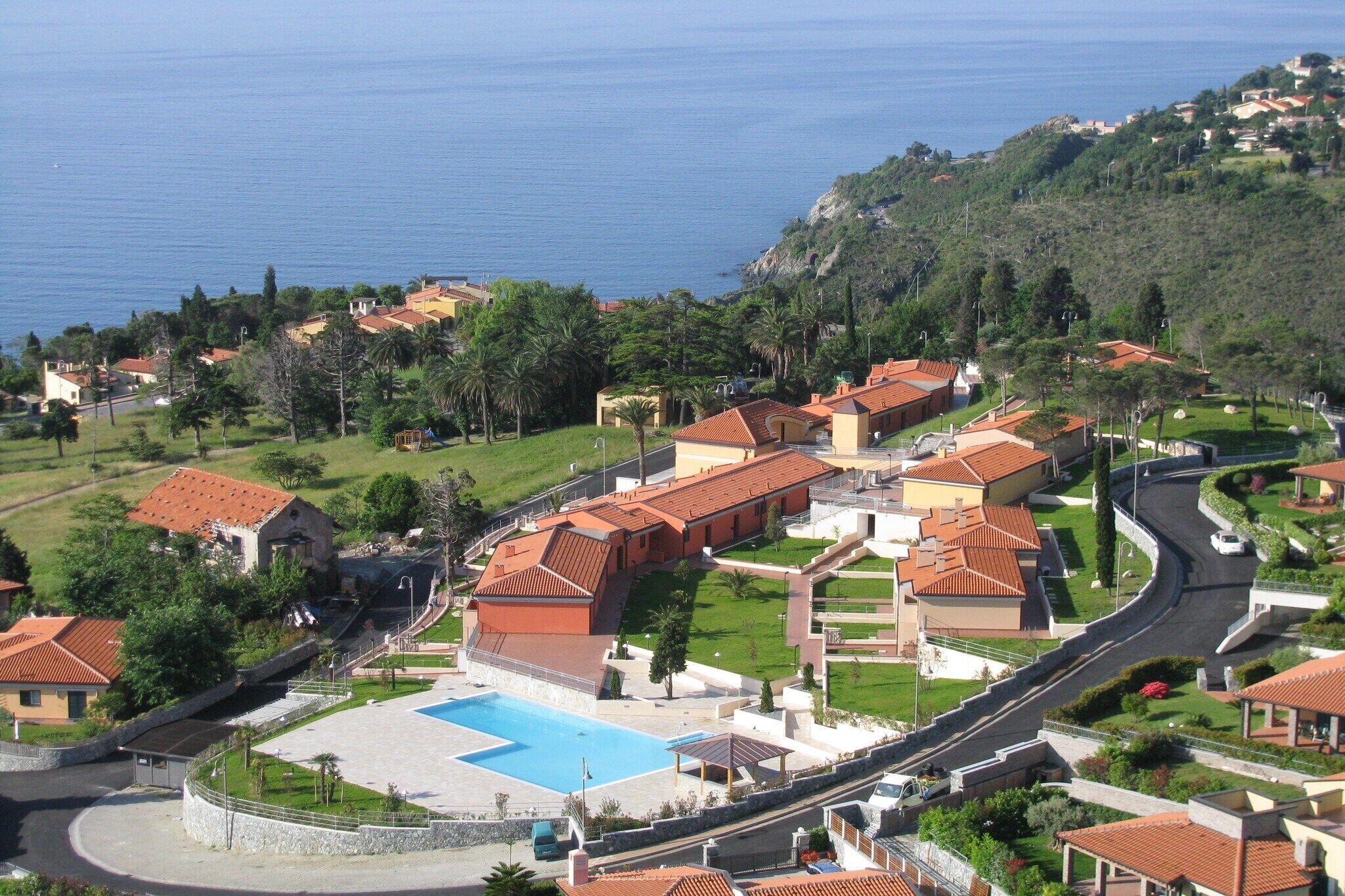 Una località balneare con piscina, edifici a terrazze e vista sul mare.