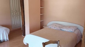 Quarto com cama, cadeira, porta e estante.