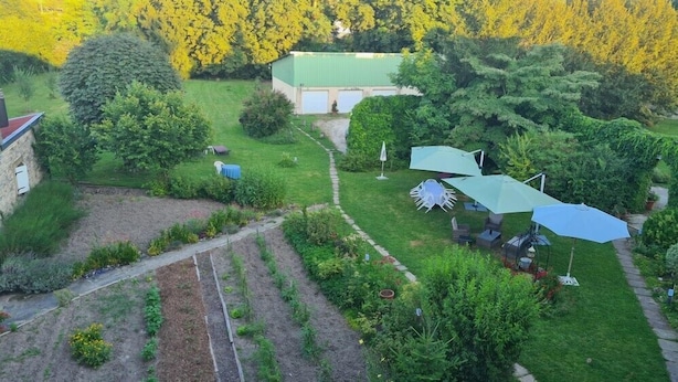 Um jardim com um edifício verde, mesas ao ar livre e um caminho.