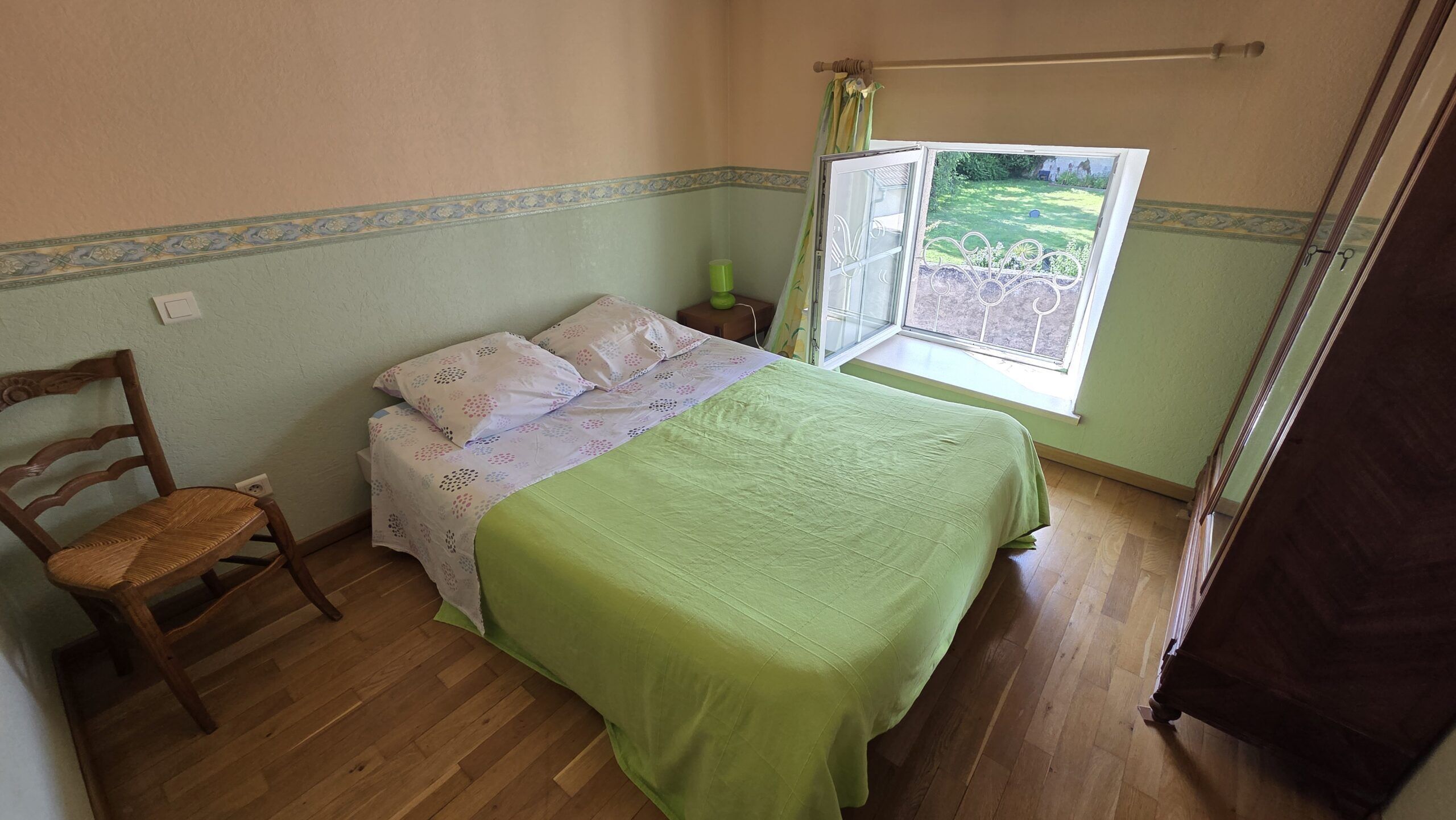 A bedroom with a bed, a chair, a window, and a curtain.