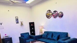 Una sala de estar moderna con un sofá azul, una mesita de centro, una lámpara y obras de arte en la pared.