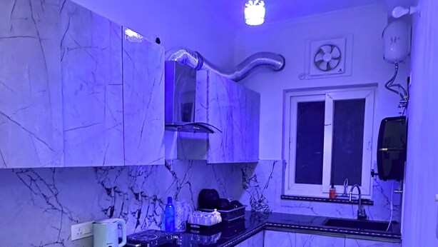 Una cocina con encimeras de mármol, salpicadero negro y ventilador de techo.