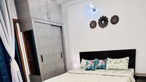 Un dormitorio con cama, armario, alfombra estampada y adornos en la pared.