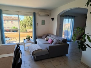 A living room with a sofa, a small table, and a chair. There is a sliding glass door leading to an outdoor area.