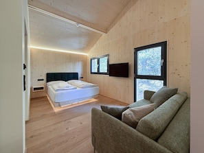 Une chambre moderne avec un lit, un canapé et de grandes fenêtres.