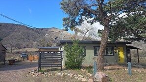 A small cabin with a fenced yard, a tree, and a mountain in the background. -  The Bisbee Vista Cabin, Cozy Desert Retreat + Mountain Views (Bisbee)