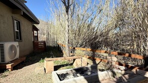 A house with a patio, a wooden deck, and a garden with bare trees. -  The Bisbee Vista Cabin, Cozy Desert Retreat + Mountain Views (Bisbee)