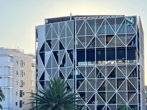 Ein modernes Gebäude mit einer geometrischen Fassade, mehreren Stockwerken und einem markanten Eingang.