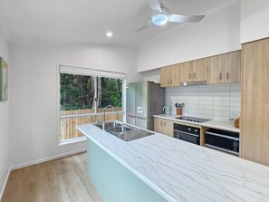 A modern kitchen with a marble countertop, wooden cabinets, and a built-in dishwasher.
