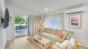 Een moderne woonkamer met een bank, salontafel en een rieten fauteuil.